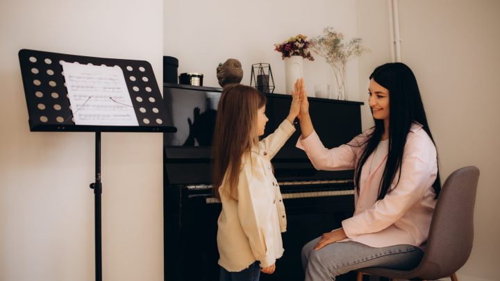 Élève prenant un cours de chant avec un professeur devant un piano.