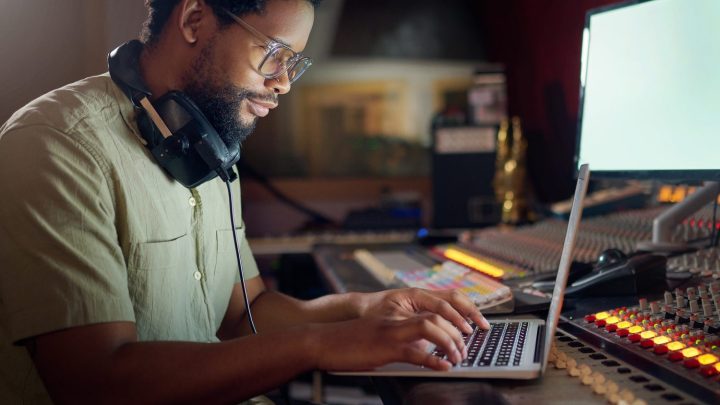 Musicien enregistrant sa voix avec un microphone relié à une interface audio dans un studio.