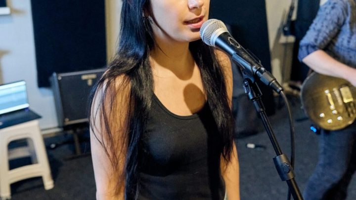 Chanteuse pratiquant des exercices vocaux dans une salle de répétition, une main posée sur son abdomen.