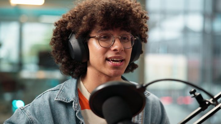 Podcasteur parlant devant un microphone de bureau dans un setup audio équipé.