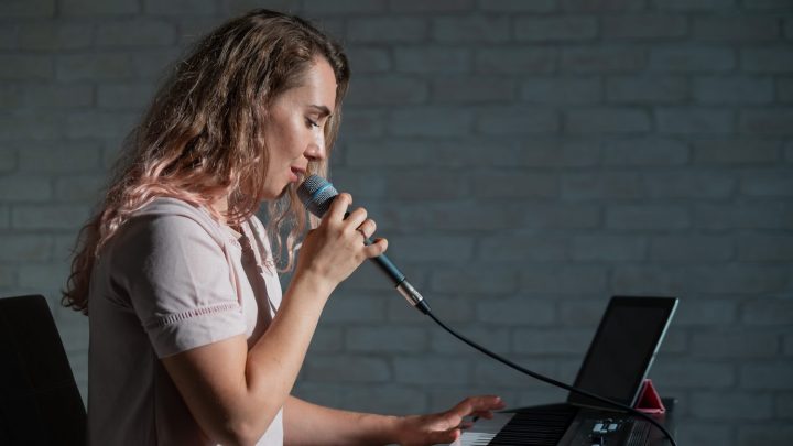Chanteuse travaillant sa justesse vocale devant un piano, avec une partition ouverte et un accordeur posé à côté.