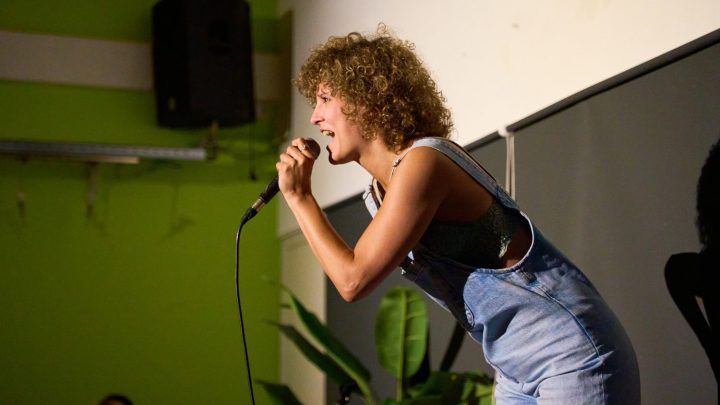 Chanteuse travaillant sa voix avec une posture détendue devant un microphone.